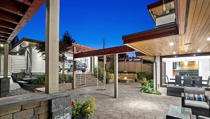Covered patio at dusk with a paved courtyard and block walls by Belgard